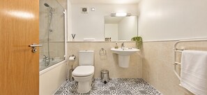 A bathroom with a toilet, sink, shower, and a mirror. - A unique apartment in the heart of central London. (London)