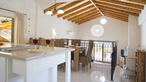 Una cocina amplia con zona de comedor, vigas de madera en el techo y vistas al exterior.