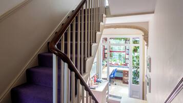 A staircase with a wooden handrail leading to a room with a desk, chair, and bookshelves.
