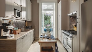 A kitchen with white cabinets, a built-in microwave, a stove, and a coffee machine.