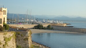 A marina with boats docked, a stone wall, and a building on the left. - Antibes Old Town, Sunny, South facing apartment 2 Balconies, fully air condition (Antibes)