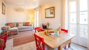 A dining area with a wooden table, red chairs, and a sofa in the background. - Antibes Old Town, Sunny, South facing apartment 2 Balconies, fully air condition (Antibes)