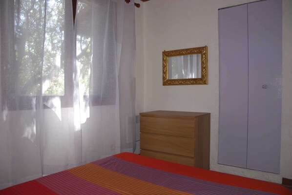 Un dormitorio con una cama, un aparador de madera, un armario y un espejo en la pared.