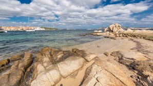 A coastal landscape with clear waters, rocky shore, and a distant town with buildings. - One bedroom apartment (4 people) - Palau Green Village (Palau)
