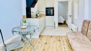 Un espacio habitable compacto con kitchenette, una zona de comedor con mesa y sillas, y un sofá.