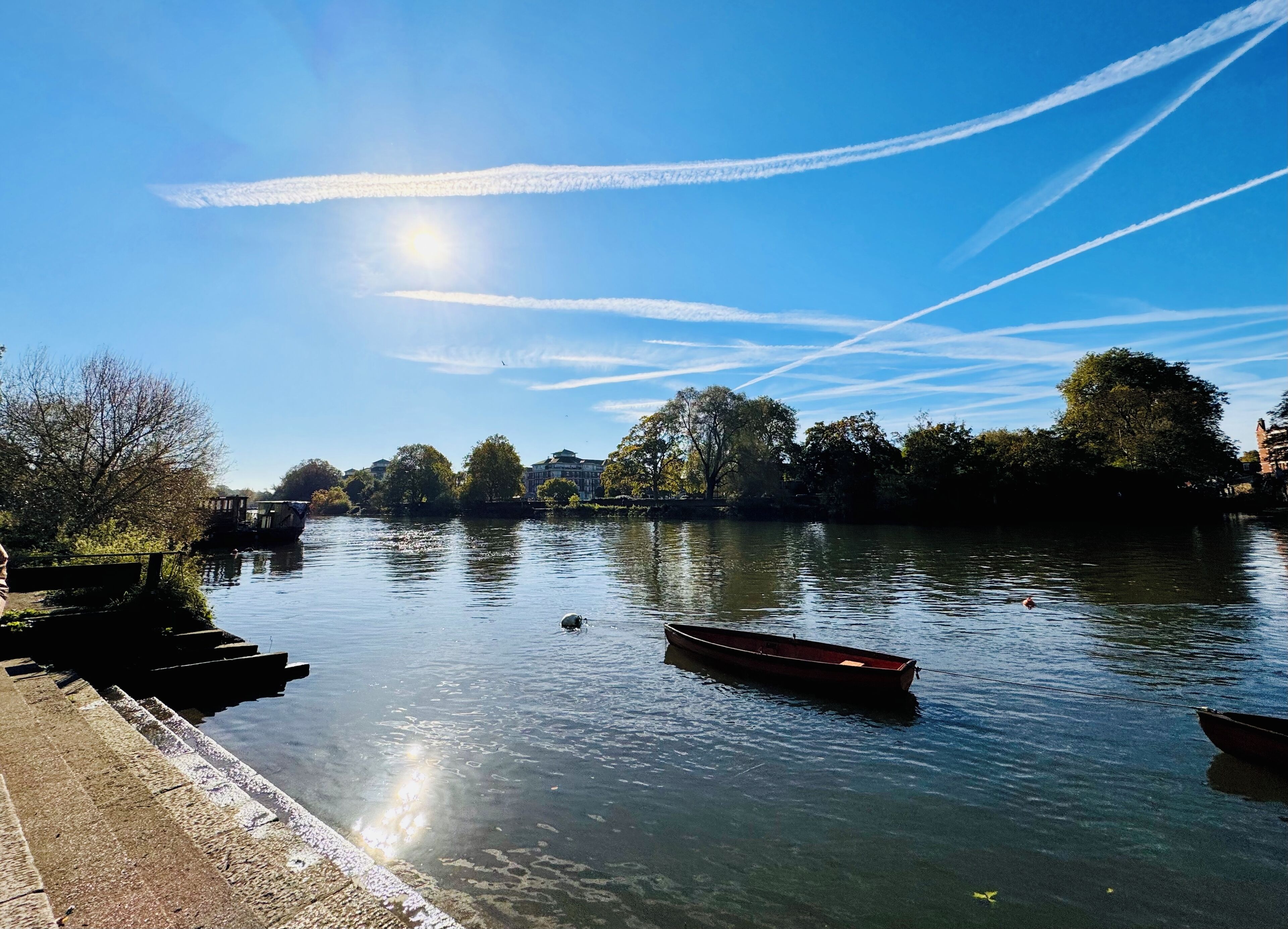 A calm river with boats, a clear sky, and trees along the banks.