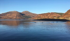A calm lake with mountains in the background and a clear sky.