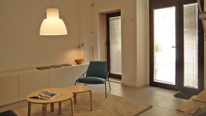 Een moderne woonkamer met een bank, een tafel, een lamp en een boekenkast.