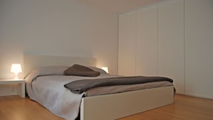 Een moderne slaapkamer met een bed, bedlampen en een kledingkast.