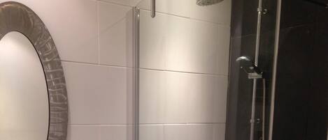A modern bathroom with a glass-enclosed shower, a white sink with a mirror, and a wooden vanity.