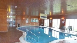 Una piscina interior amb interior de fusta, un senyal que indica la profunditat de l'aigua i una zona de seients amb taules i cadires.