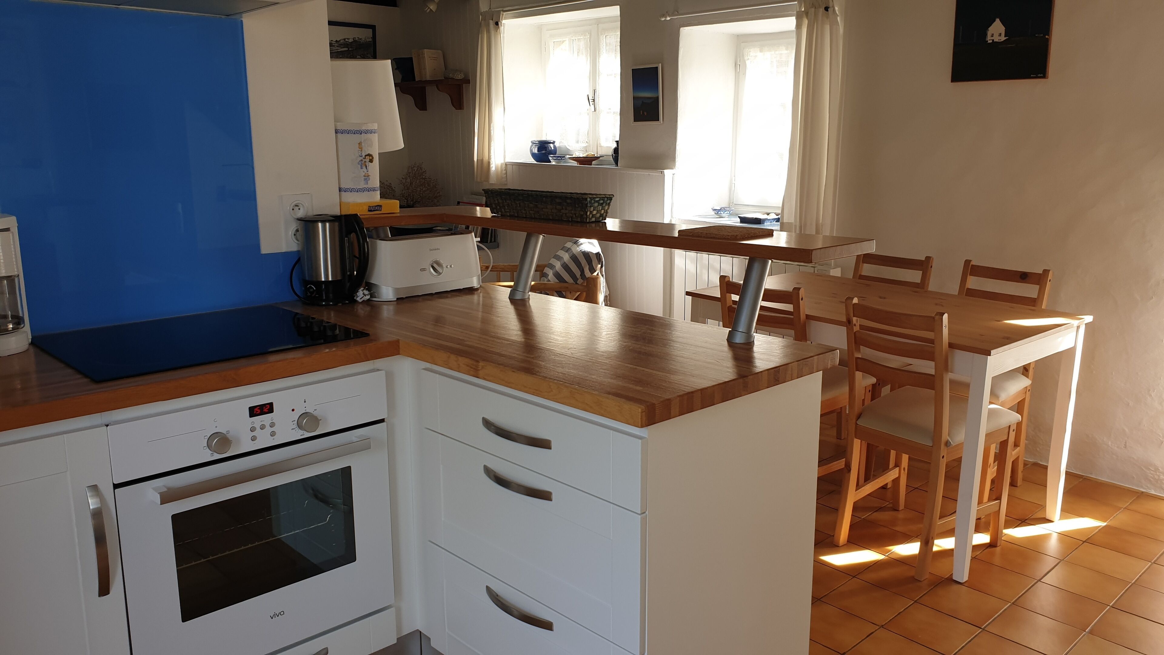 A compact kitchen with a stove, oven, and a dining area with chairs and a table.