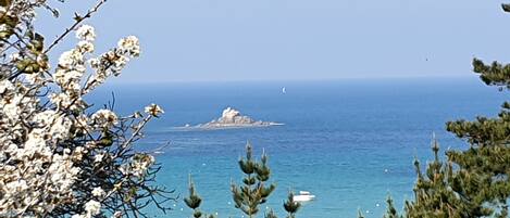 A coastal landscape with a rocky island and clear blue sea.