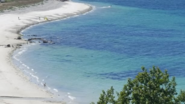 Ein Strand mit klarem, blauem Wasser und weißem Sand.