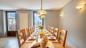 Een eetkamer met een lange houten tafel, gedekt voor een maaltijd, omringd door houten stoelen.