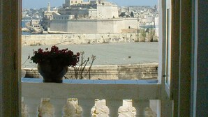 Blick von einem Balkon mit Geländer auf eine Stadtlandschaft mit Gebäuden und einem Gewässer.