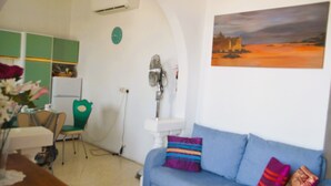 Ein Wohnzimmer mit einem blauen Sofa, einem grünen Sessel, einem weißen Tisch und einem Bild an der Wand.