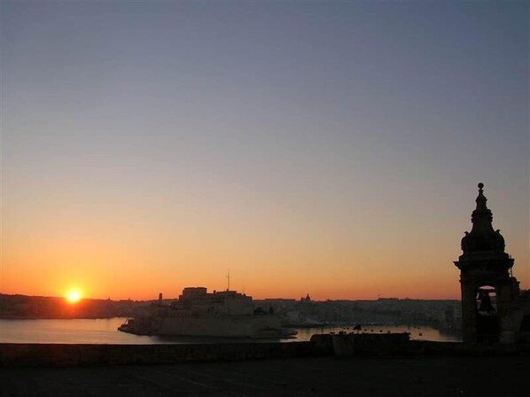 A sunset over a cityscape with a prominent tower silhouette. - Grand Harbour, Valletta, Malta - sleeps six (Ta'Liesse)