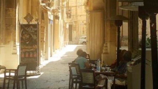 Eine Stadtstraße mit einem Café unter einem Bogen.