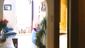 Ein Innenbereich mit einem Holztablett, Stühlen, einer Hängelampe und einem Blumentopf.