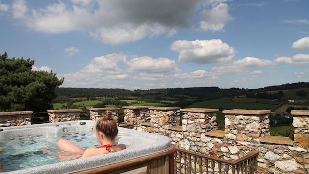 A hot tub with stone walls and a view of green fields and hills. - Sleeps 16,, Indoor Heated Pool, Rooftop Hot Tub, Devon Coast Views, Pets welcome (Honiton)