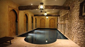 A swimming pool with stone walls and wooden beams, benches, and hanging lights. - Sleeps 16,, Indoor Heated Pool, Rooftop Hot Tub, Devon Coast Views, Pets welcome (Honiton)