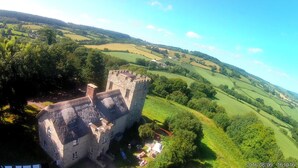 A historic stone castle with a tower, surrounded by lush green fields and trees. - Sleeps 16,, Indoor Heated Pool, Rooftop Hot Tub, Devon Coast Views, Pets welcome (Honiton)