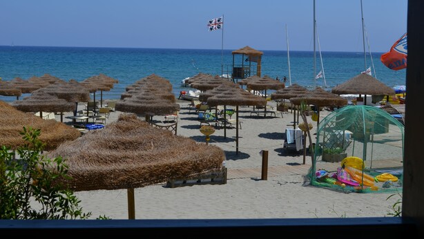 A beach with thatched umbrellas, a lifeguard tower, and a netted play area. - Charming house/villa panoramic sight on sea 6 persons (Villaputzu)