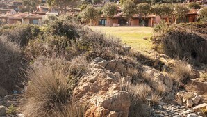 A rocky landscape with sparse vegetation and a distant view of Mediterranean-style houses. - Charming house/villa panoramic sight on sea 6 persons (Villaputzu)