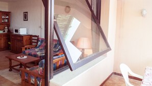 A living room with a sofa, a wooden table, a cabinet, and a window with a view of the outside. - Charming house/villa panoramic sight on sea 6 persons (Villaputzu)