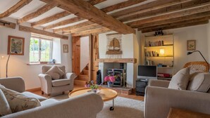 Una sala de estar acogedora con vigas de madera a la vista, una chimenea y una estantería.