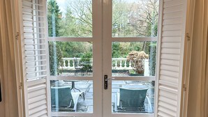 A double French door with a view of outdoor seating and greenery.