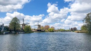 Een rivier met windmolens en huizen langs de oevers.