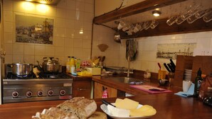 Een keuken met een fornuis, potten, een houten aanrecht en diverse keukengerei.