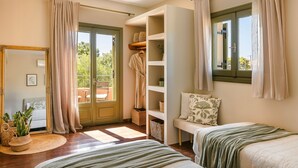 Ein Schlafzimmer mit zwei Betten, einem Einbauschrank, einer Sitzecke und einem Balkon.