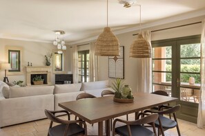 A dining area with a wooden table and chairs, a sofa, and hanging wicker lamps.