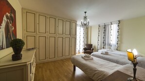 A hotel room with two beds, a chandelier, a chair, a desk, and a painting on the wall. - Appartamento storico con balconi vista Arena (Verona)
