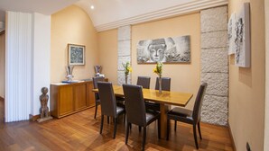 A dining area with a wooden table and chairs, a stone accent wall, and a Buddha statue. - Appartamento storico con balconi vista Arena (Verona)