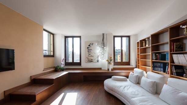 A modern living room with a white sofa, wooden bookshelves, a flat-screen TV, and a staircase leading to a balcony. - Appartamento storico con balconi vista Arena (Verona)