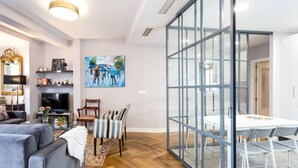 A modern living room with a grey sofa, a TV, and a painting on the wall. - Seville center, large penthouse with terrace and 3 double bedrooms (Sevilla)