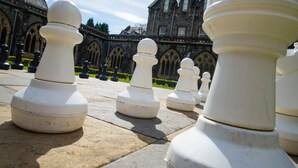 A series of white chess pieces arranged on a stone pavement in front of a historic building with gothic architecture. - 3 bedroom 2nd floor apartment to sleeping 8 with stunning views of Loch Ness. (Loch Ness)