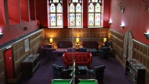 A room with a pool table, red sofas, and wooden paneling. - 3 bedroom 2nd floor apartment to sleeping 8 with stunning views of Loch Ness. (Loch Ness)
