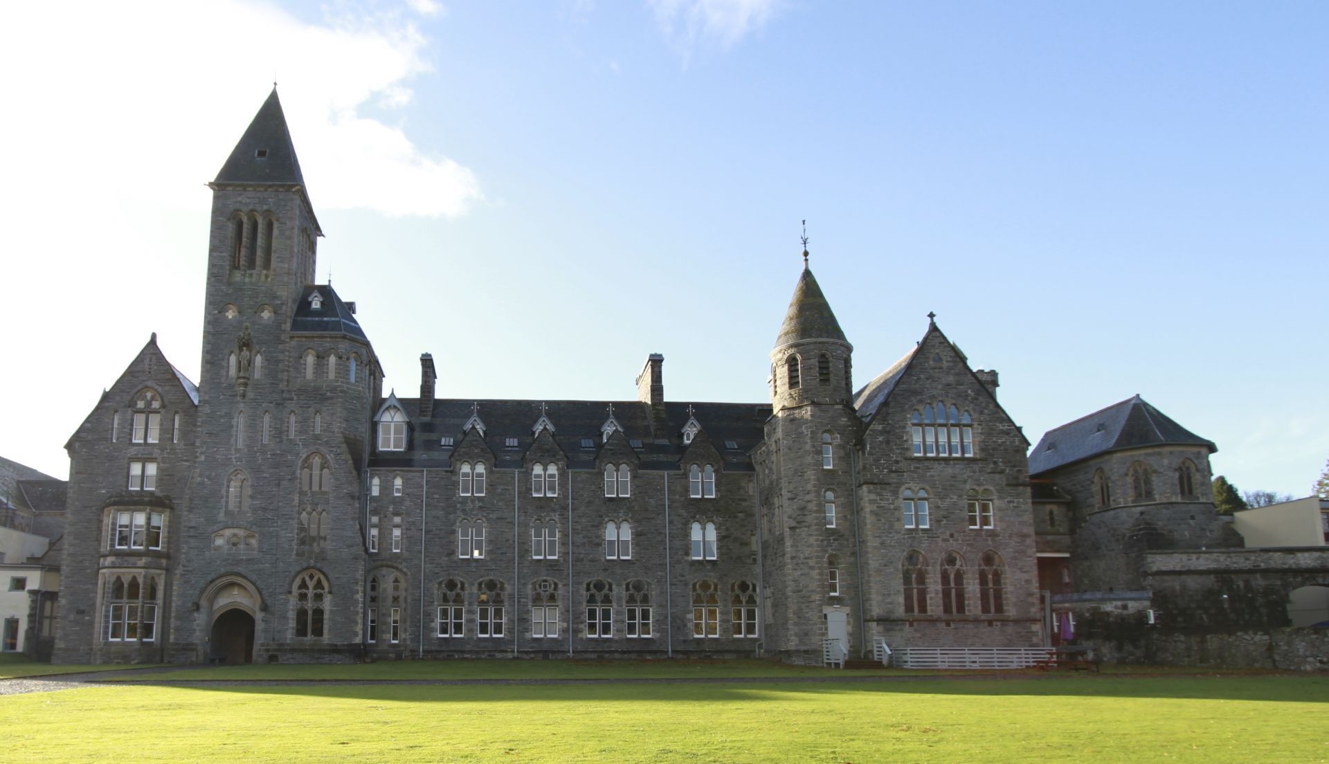 A large, historic stone building with multiple towers and arched windows, likely a castle or manor house.