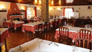 Een restaurant met meerdere tafels gedekt voor dineren, houten wanden en een open haard.