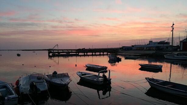 Een rustige haven bij zonsondergang met enkele aangemeerde boten.