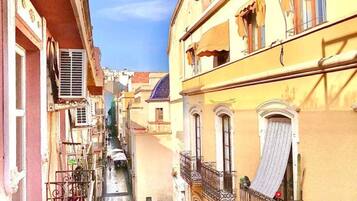 Une rue étroite, bordée de bâtiments des deux côtés, avec des balcons et un ciel dégagé.