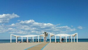 Een strand met witte parasols en een heldere lucht.