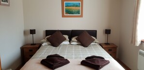 A neatly made bed with two pillows, two bedside tables with lamps, and a framed picture on the wall.