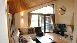 Ein modernes Wohnzimmer mit Sofa, Couchtisch, Fernseher und Kamin.