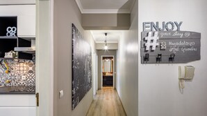 A hallway with a wooden floor, a wall-mounted sign that reads "ENJOY your stay @ Kwadalayo Art Quarters", and a telephone on the right. - Kwadalayo Art Quarters (Faro)